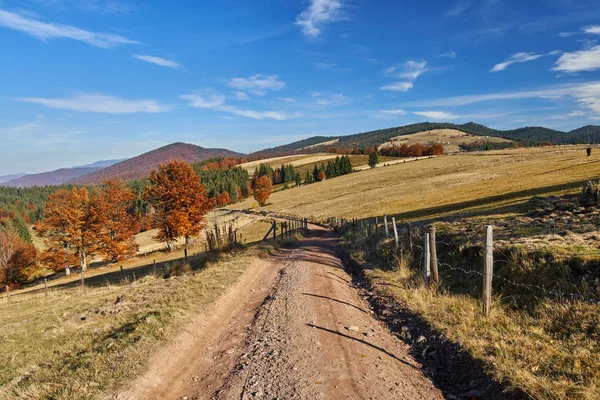 Estrada de terra através da paisagem outonal — Fotografia de Stock