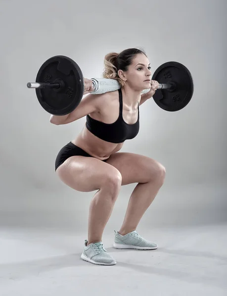 woman doing squats with barbell