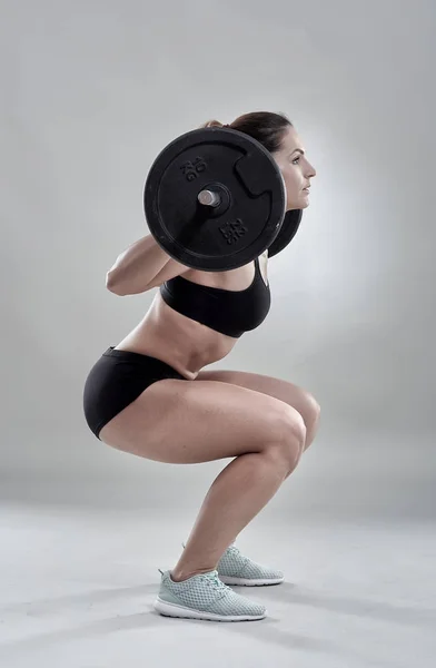 Woman doing squats with barbell — Stock Photo, Image