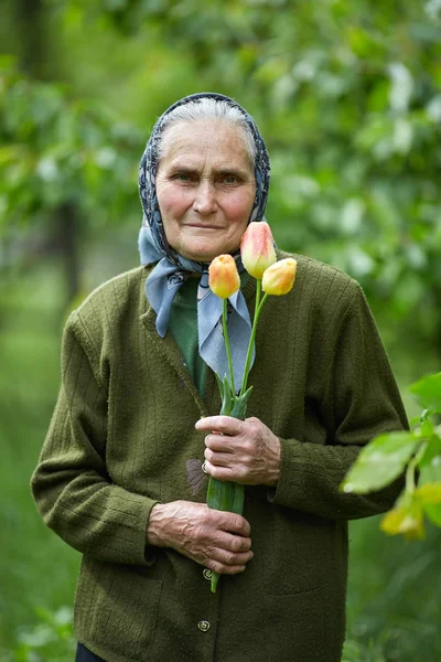 Old woman with flowers — Stock Photo, Image