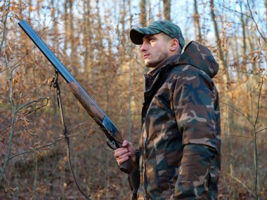Hunter çift namlulu av tüfeği ile kamuflaj elbiseli