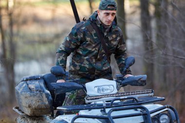 Ormanın içinde oyun için arama bir quad bisiklet üzerinde genç avcı