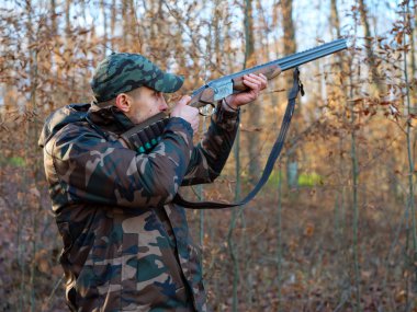 Hunter çift namlulu av tüfeği ile kamuflaj elbiseli