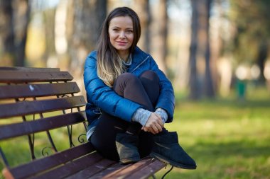 Parktaki bankta oturan genç bir kadın.