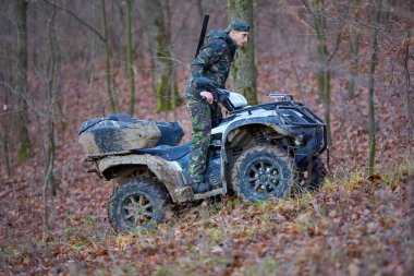 Ormanın içinde oyun için arama bir quad bisiklet üzerinde genç avcı