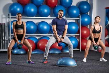 Fitness Eğitmeni kettlebell ile çalışma dışarı iki kızla