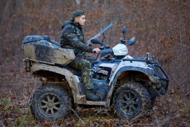 Ormanın içinde oyun için arama bir quad bisiklet üzerinde genç avcı