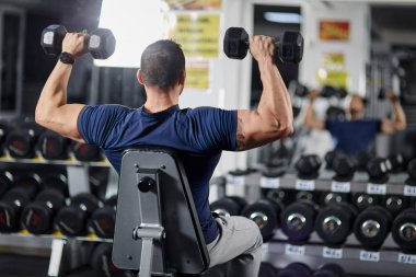 Spor salonunda dumbbells ile omuz egzersiz yapan erkek