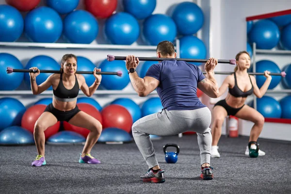 Fitness Eğitmeni ve bacaklar için fitbar egzersiz yapıyor öğrenciler