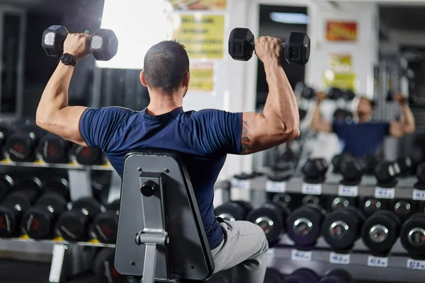 Spor salonunda dumbbells ile omuz egzersiz yapan erkek