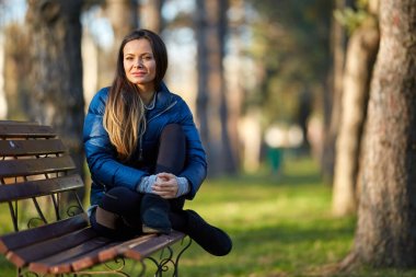 Genç kadın bankta oturuyor.