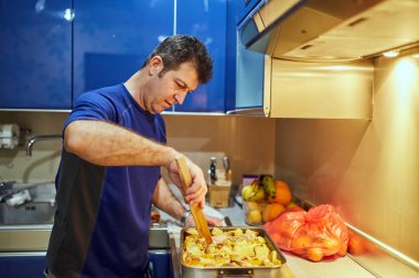 Orta yaşlı adam evde yemek tavuk davul fırın tepsisinde