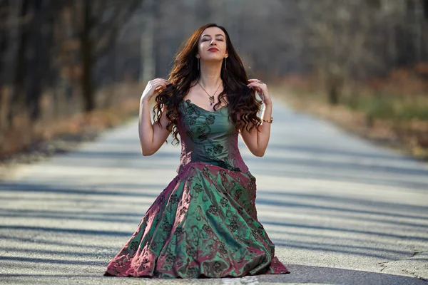 Kvinna i klänning som sitter på vägen — Stockfoto