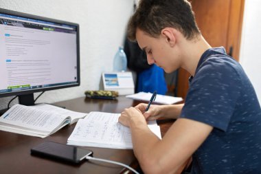 Özenle ödev ile bilgisayar masasında öğrenci