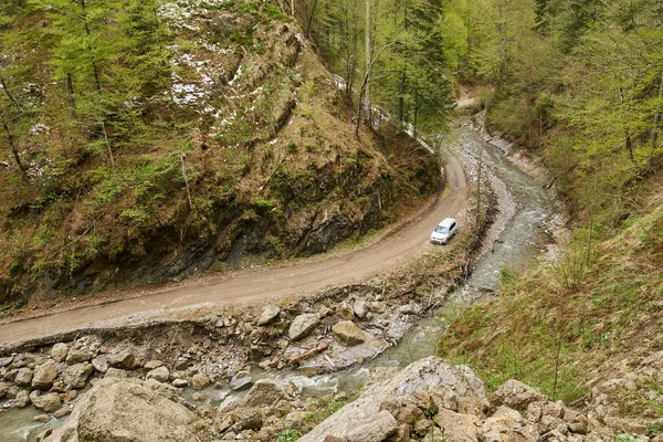Aerial shot of an offroad car on muddy road in mountains