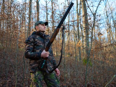 Çift namlulu av tüfeği ile kamuflaj takım elbise avcı