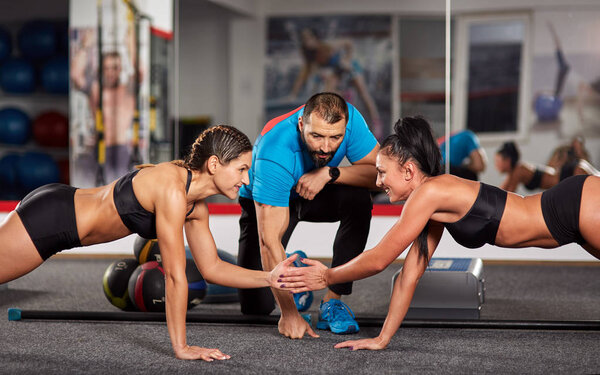 Fitness trainer and women doing crossfit workout in gym and disputing who stronger