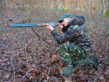 Çift namlulu av tüfeği ile kamuflaj takım elbise avcı