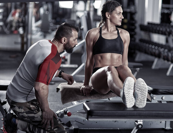 Coach assisting woman with triceps dips on bench