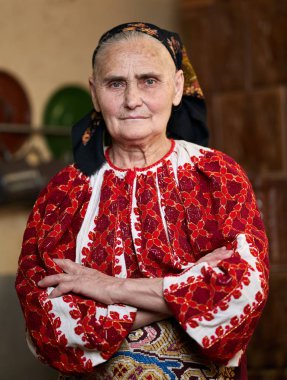 Silah katlama ve kameraya bakarak geleneksel Kostüm giymiş eski Rumen kadın