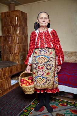 Sepet elma dolu tutan geleneksel kostüm giyen yaşlı çiftçi kadın
