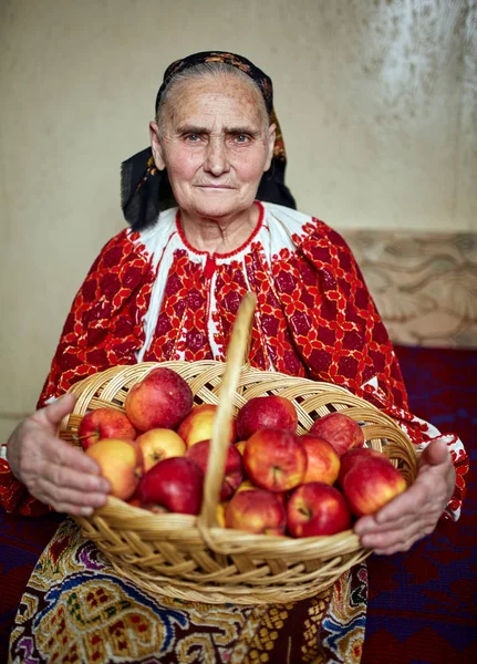 老农夫妇女在传统服装藏品篮子装满苹果 — 图库照片