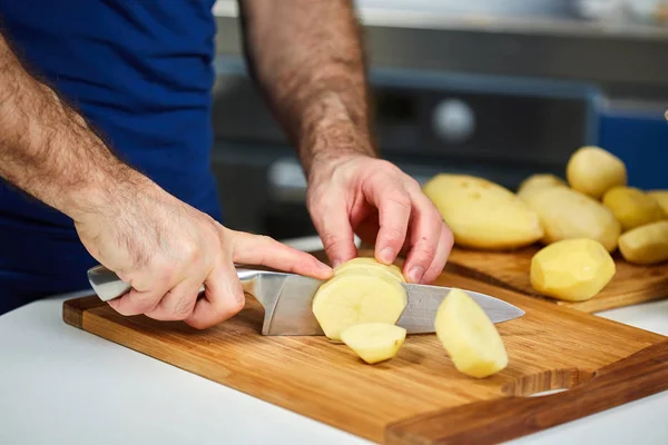 Homem cortando batatas em um tabuleiro — Fotografia de Stock
