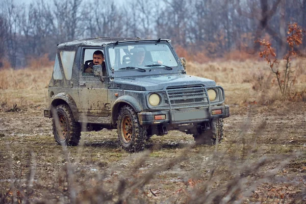 古いオフロード車で森の泥の中を行く 人の男性 — ストック写真