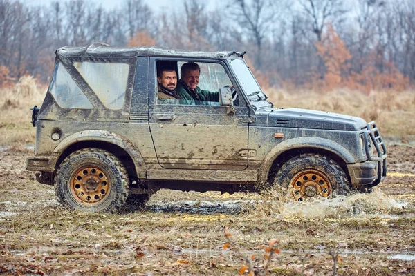 两个人在老越野车穿过森林里的泥巴 — 图库照片