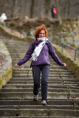 Kızıl saçlı kadın Park'taki eski taş merdivenle aşağı sırt çantası ile