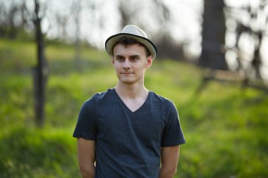 Kırsal kesimde T-shirt ve bej şapka giymiş yakışıklı genç closeup portresi