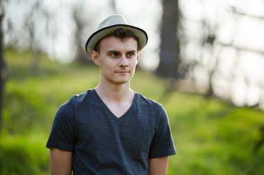 Kırsal kesimde T-shirt ve bej şapka giymiş yakışıklı genç closeup portresi