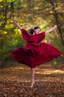 Ormanda dans eden kırmızı elbiseli genç kız.