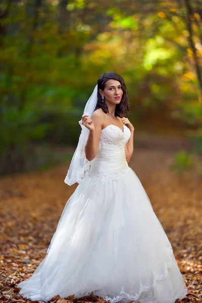 Candid portrait of a beautiful bride in her wedding dress in the forest