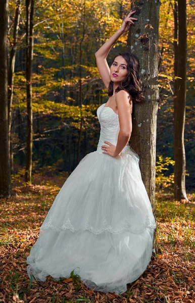 Candid portrait of a beautiful bride in her wedding dress in the forest