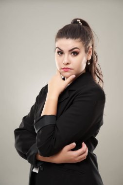 Genç bir iş kadınının eli çenesinde ve düşünüyor.