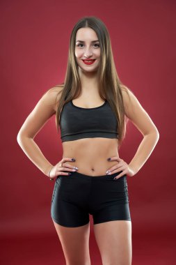 Güzel genç bayan kırmızı arka planda egzersiz yapıyor.