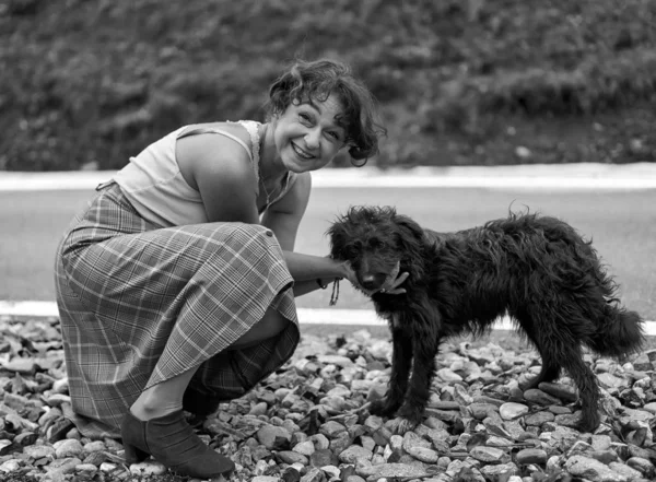 田舎道の近くの野良犬と遊ぶ女 — ストック写真