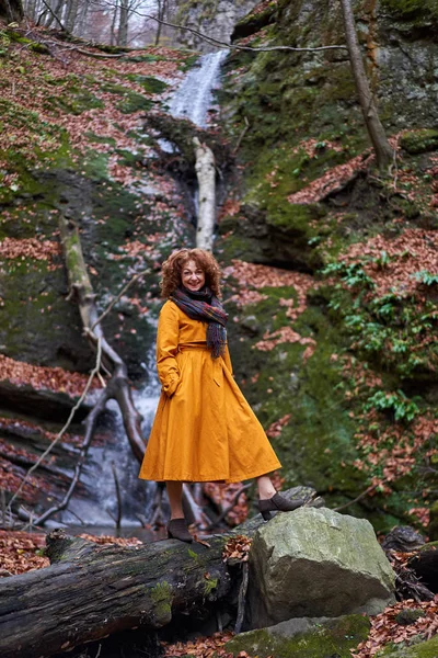 瀑布边穿着黄色外套的成熟女人的画像 — 图库照片