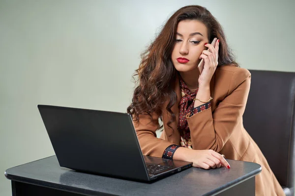 Młoda Kobieta Interesu Mówiąc Jej Telefon Patrząc Laptopa — Zdjęcie stockowe