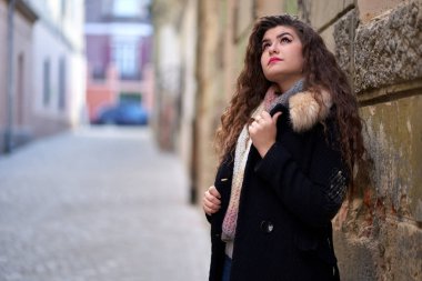 Şehir ortamında genç bir kadın, yaşlı bir kasaba.
