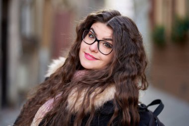 Açık havada uzun dalgalı saçları olan genç bir kadının yakın çekimi.