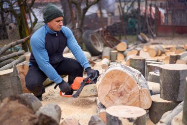 Oduncu testere ile kayın kütükleri üzerinde çalışıyor.