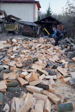 Kırsal adam arka bahçesinde balta ve pençe ile odun kırıyor.