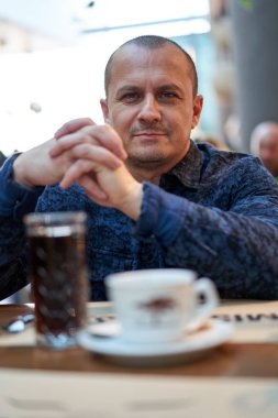 Barda bir masada oturan orta yaşlı bir adam.