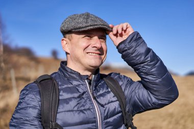 Kapaklı ve sırt çantalı bir adamın yakın çekimi.