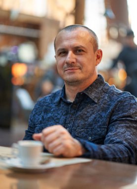 Barda bir masada oturan orta yaşlı bir adam.