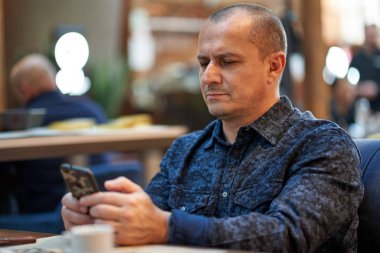 Barda bir masada oturan orta yaşlı bir adam.