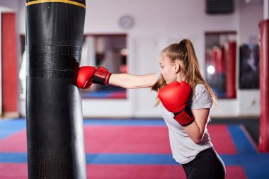 Ağır kum torbası üzerinde çalışan genç kadın savaşçı