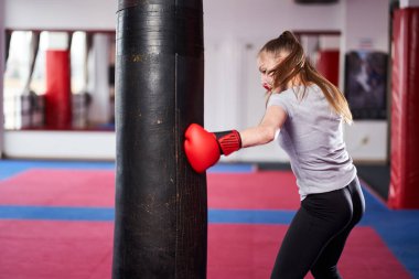 Ağır kum torbası üzerinde çalışan genç kadın savaşçı